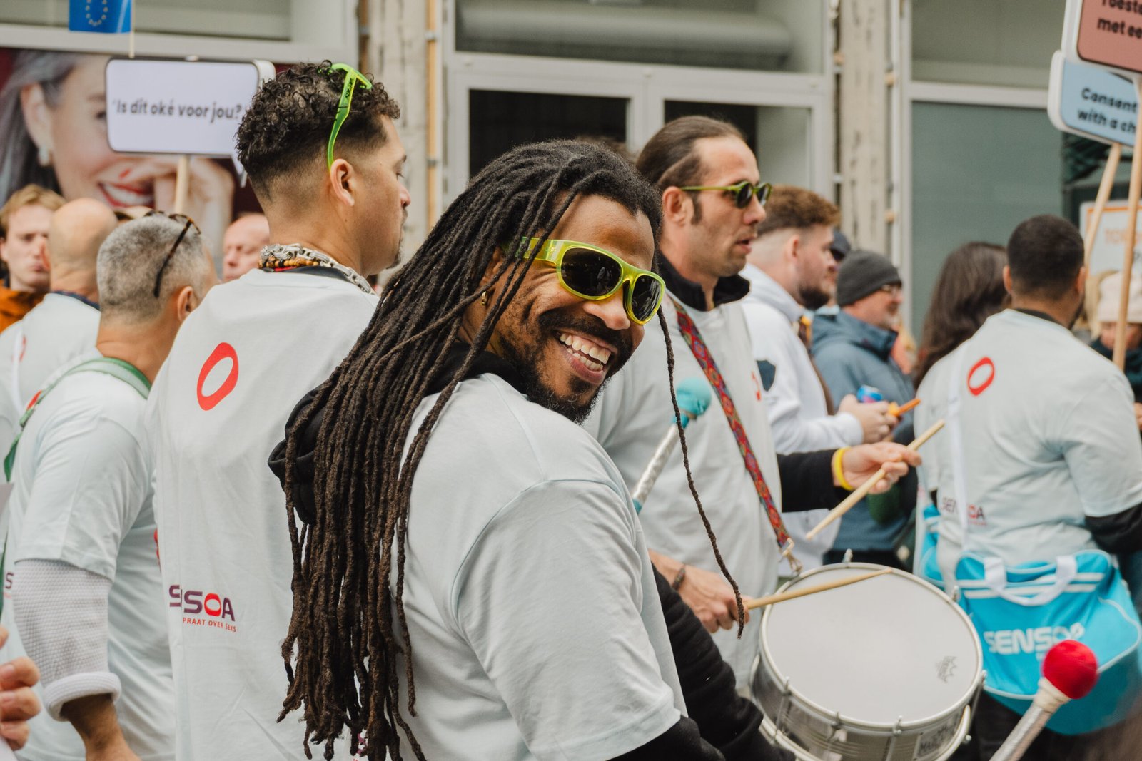 Smiling drummer at a vibrant pride parade.