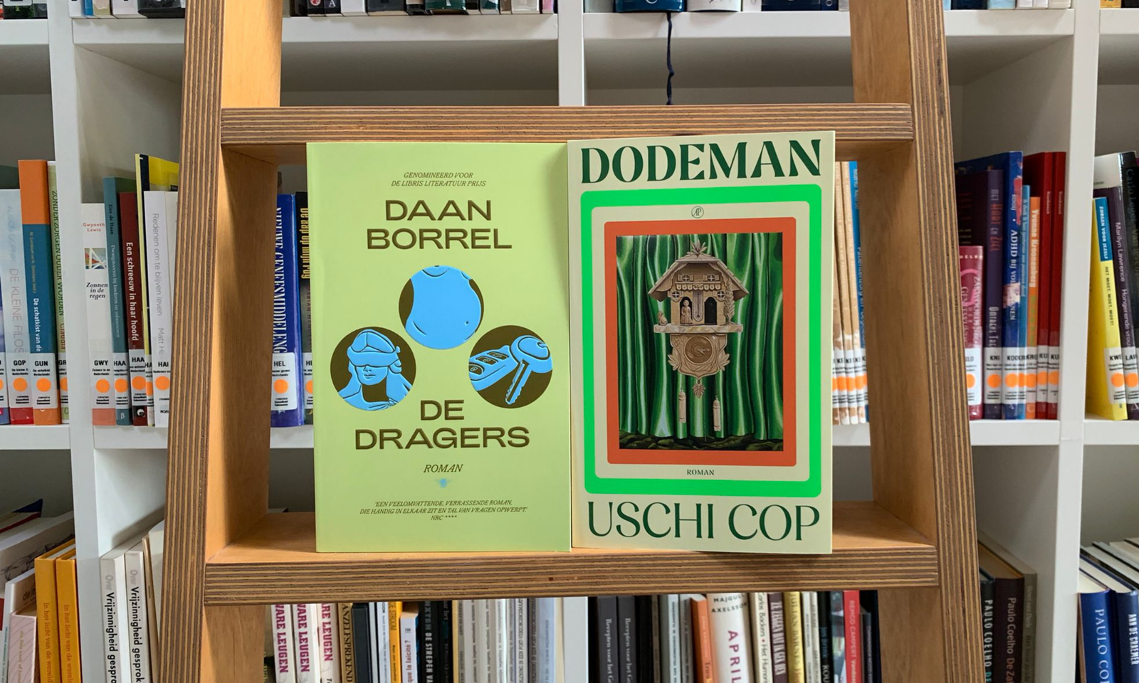 De boeken ‘Dodeman’ van Uschi Cop en ‘De Dragers’ van Daan Borrel gefotografeerd voor een boekenkast.