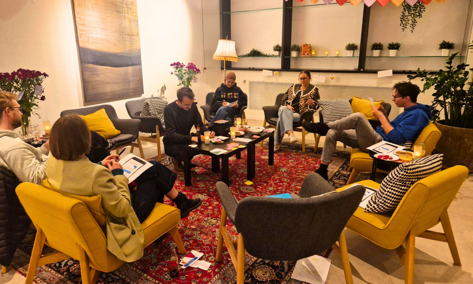 De foto toont een groep jonge mensen die samen in een boekenclub een boek aan het bespreken zijn in een cirkel.