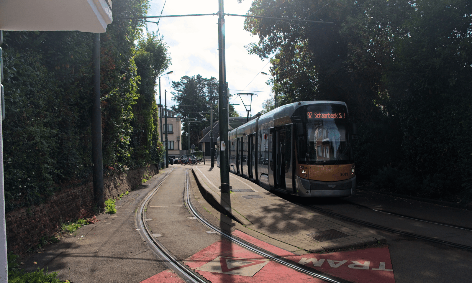 Een foto van een tramlijn door een residentiële wijk in Ukkel. Op één spoor staat tram 92 richting Schaarbeek Station te wachten.