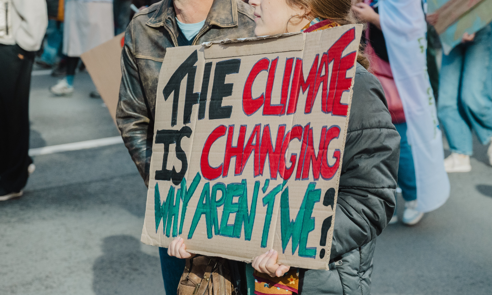 Een pancarte met de tekst: “The climate is changing why aren’t we?” op.